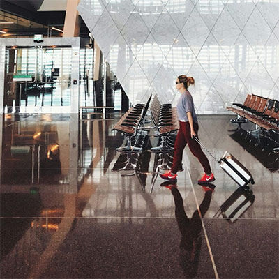 Spacious modern airport terminal with glass and metal architecture and a woman pulling luggage.