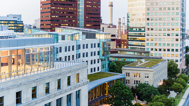Aerial view of MIT Sloan School buildings with green rooftops, modern architecture, and surrounding cityscape.