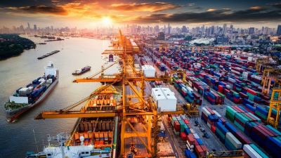 image of a port with large ships and shipping containers near a city