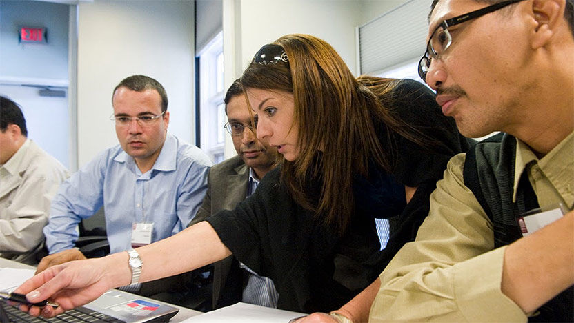 Group of professionals collaborating around a laptop during a workshop or training session.