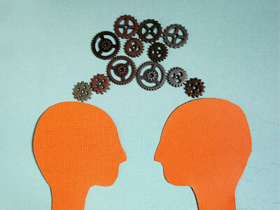 two heads facing each other with gear thought bubbles