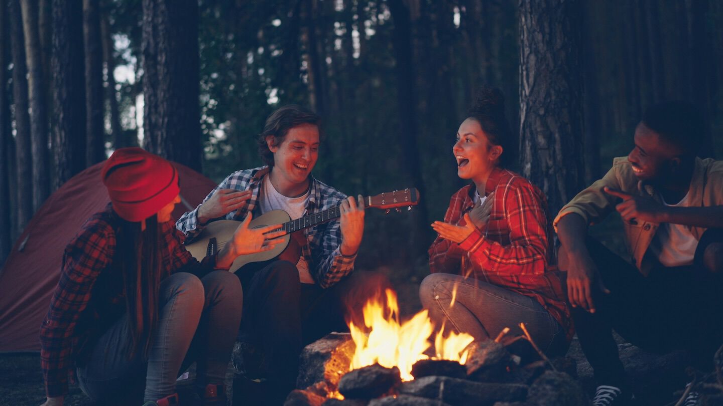 four people around a bond fire in the forest