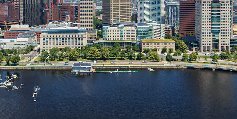Aerial view of MIT Sloan campus and surrounding buildings along the Charles River with sailboats in the water.