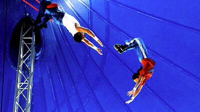 trapeze artists flying through air against blue backdrop