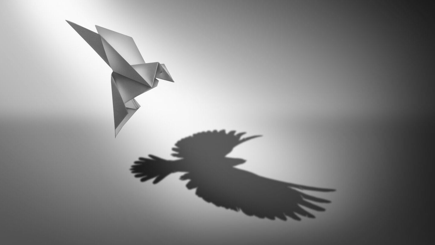 origami paper bird casting a shadow of powerful real wings