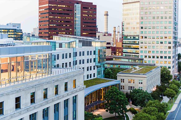 Aerial view of MIT Sloan campus surrounded by modern buildings and green rooftops in Cambridge, MA.