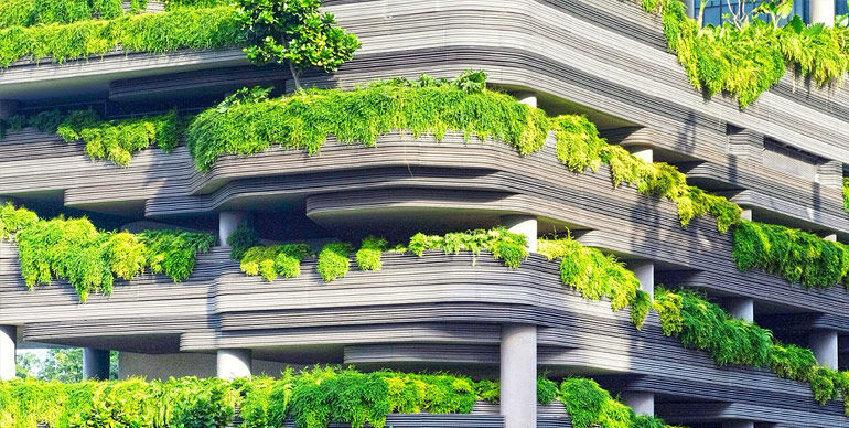 Modern building facade with cascading layers of lush greenery and contemporary architecture.