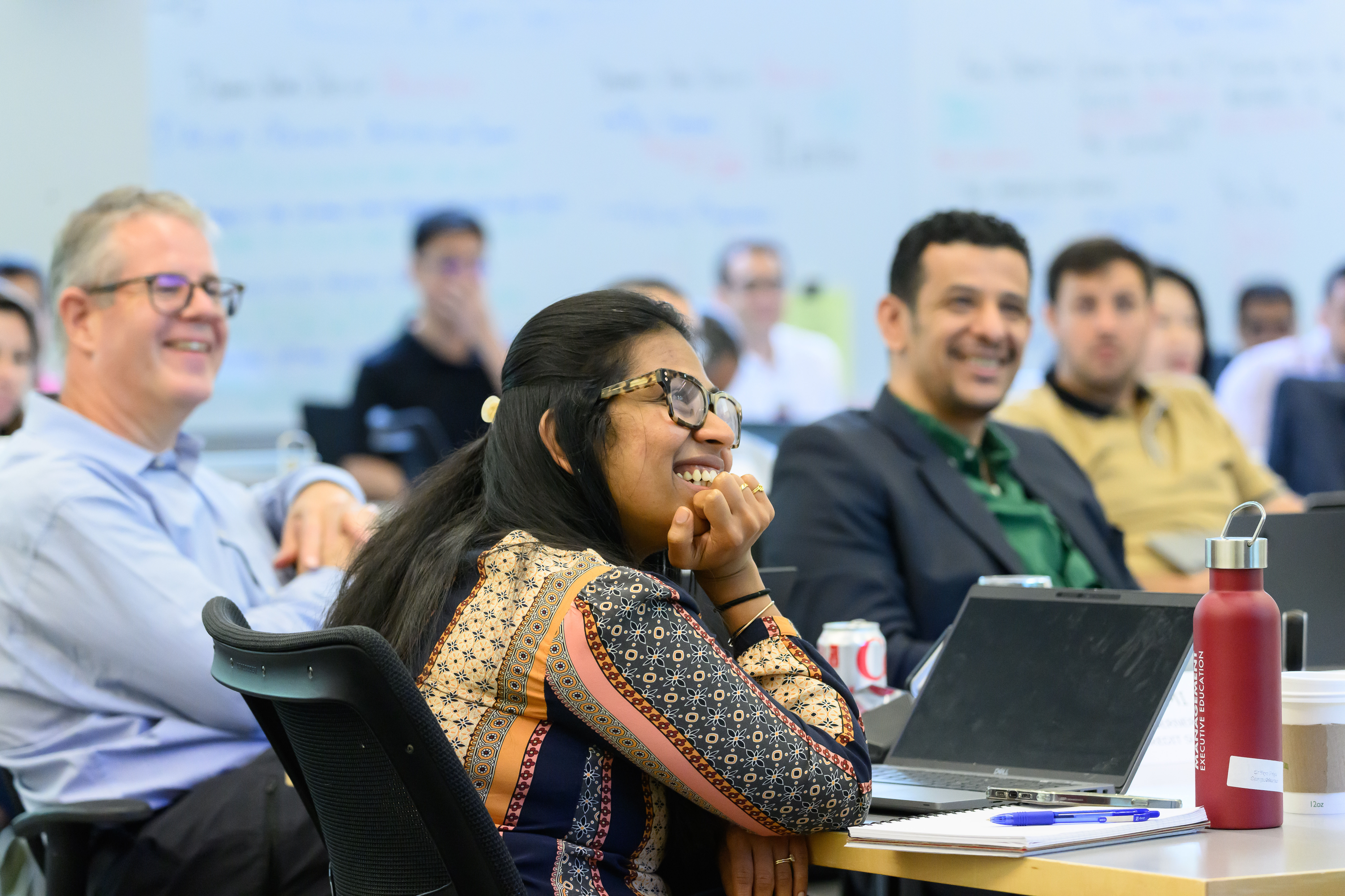 Female executive smiling in a classroom of peers.