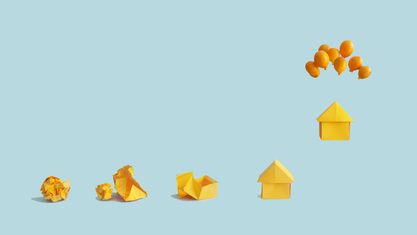 Paper house floating from being tied to balloons with other house behind. image number null