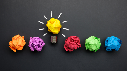 Crumpled paper balls of different colors with one representing a lightbulb. image number null
