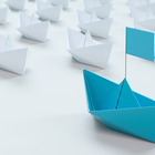White paper boats in a row with single blue boat in front.