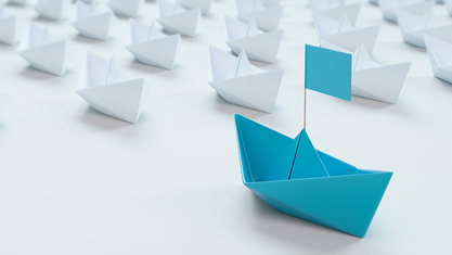 White paper boats in a row with single blue boat in front. image number null