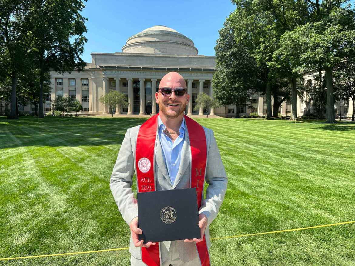 Joshua Gayman with his MIT Advanced Certificate for Executives infrom of the MIT dome