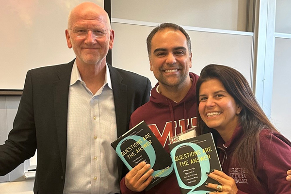 Carla Silvado and her husband with Hal Gregerson holding copies of the book Questions Are the Answer