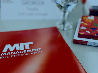 Shot of classroom desk materials -MIT folder, faculty book, nametag in background