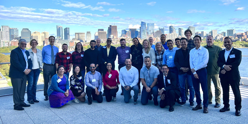 class photo of Negotiation for Executives featuring roughly 30 people (participants and faculty) standing on an outdoor patio with the Boston skyline in the background
